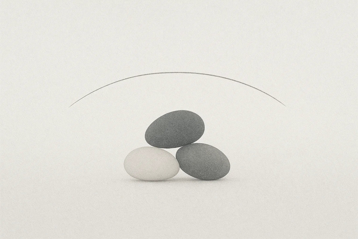 Three smooth balanced stones beneath a thin curved line, a minimalist still life symbolizing balance and goals