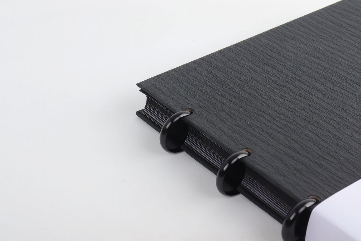 Close-up of the Black discbound notebook's textured cover and metal disc-binding rings