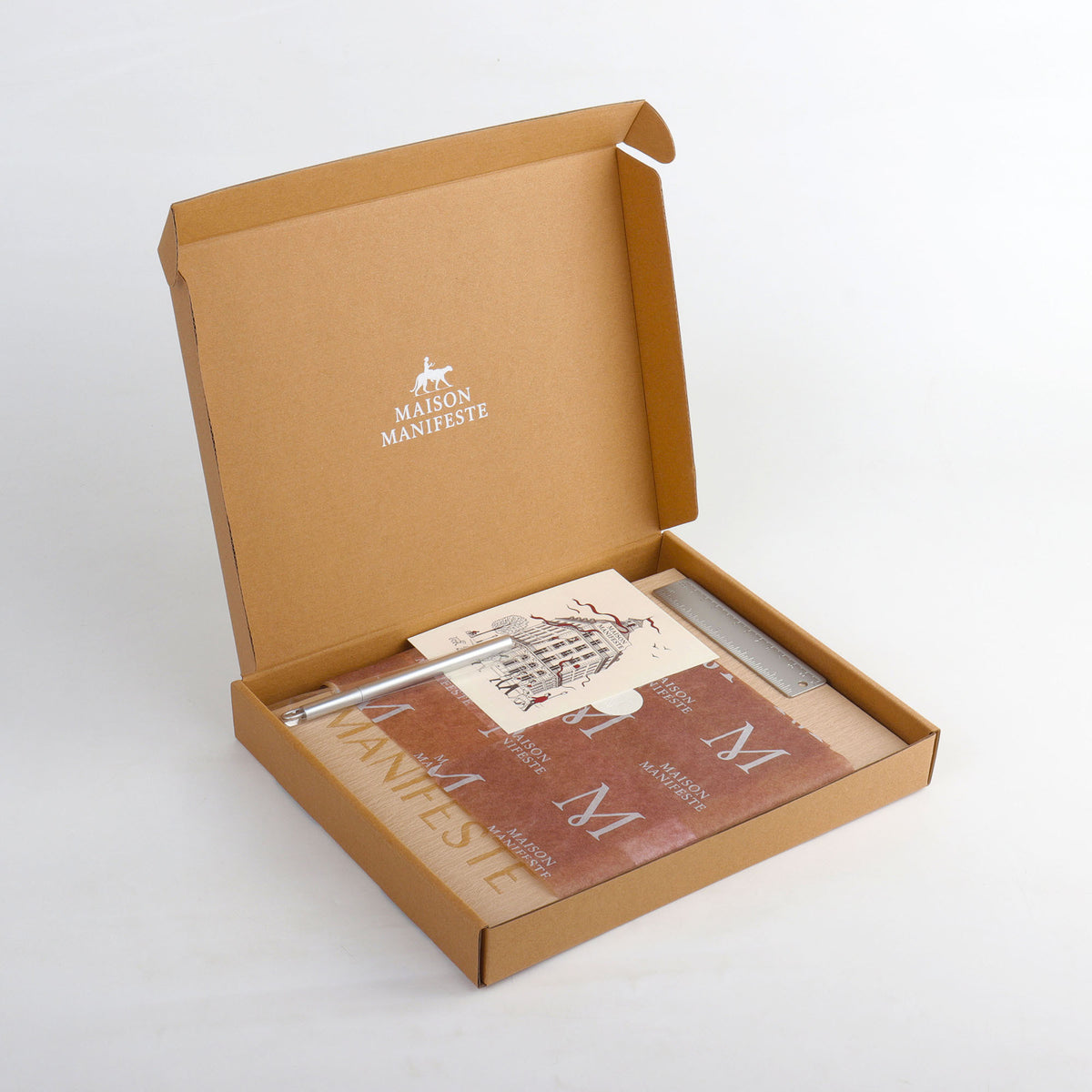 Open kraft gift box with Maison Manifeste luxury wrapping paper, sticker, and thank-you card